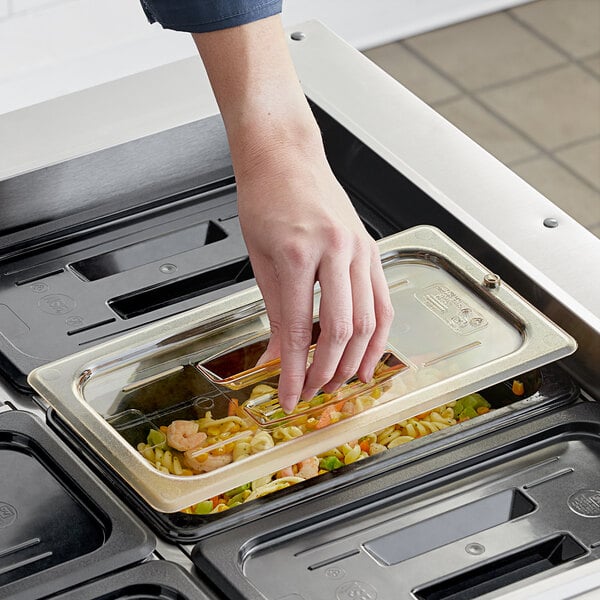A hand opening a Cambro 1/3 size amber plastic food pan lid on a food container.