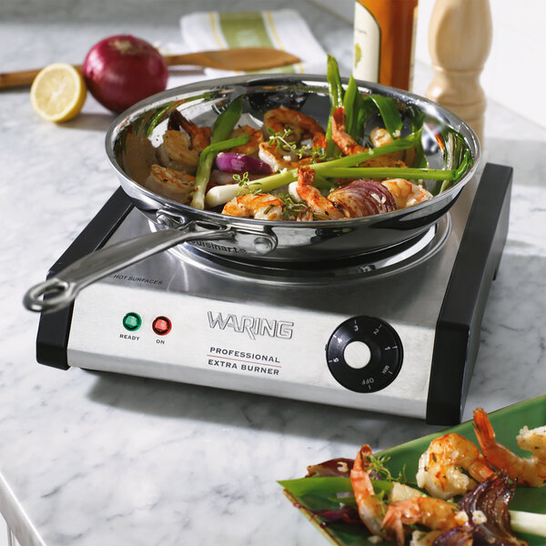 A Waring countertop range with a pan of shrimp and vegetables on it.