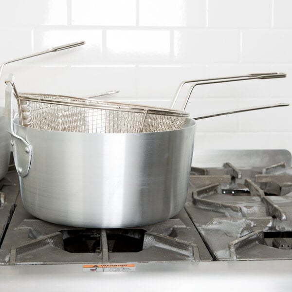 A close-up of a silver Winco aluminum fryer pot on a stove.