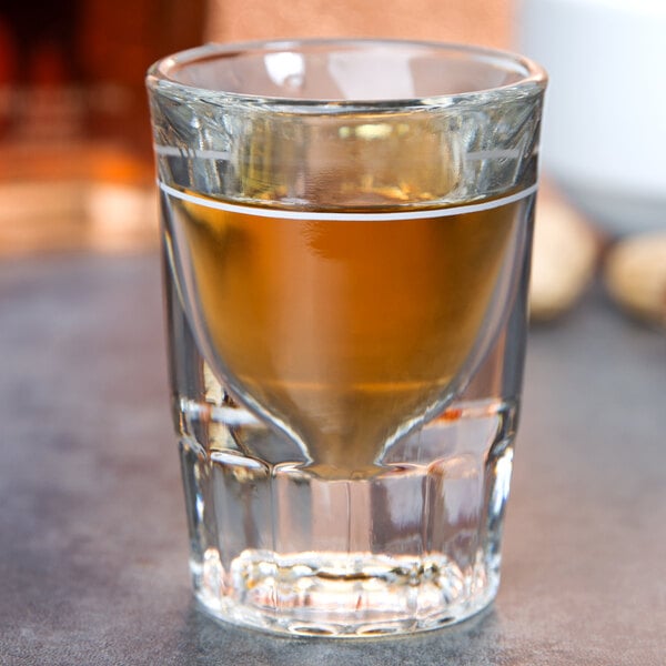 A Libbey fluted shot glass with a .75 oz. pour line filled with brown liquid.
