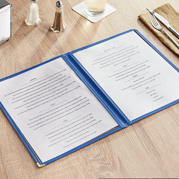 A blue Choice 4-view menu cover on a table with silverware.