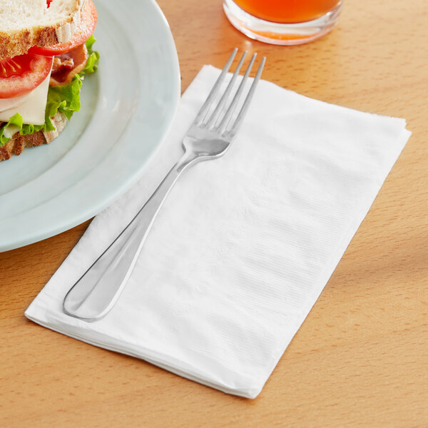 A fork and knife on a EcoChoice bamboo dinner napkin next to a sandwich.