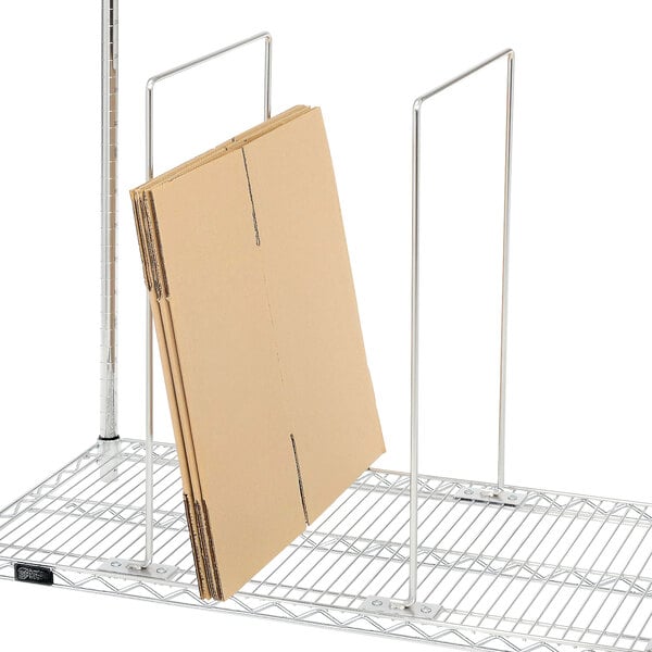 A Quantum wire shelf divider on a metal shelf with a cardboard box on it.