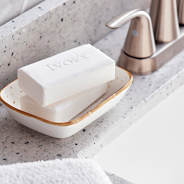 A soap dish with Ivory bar soap on a counter top.