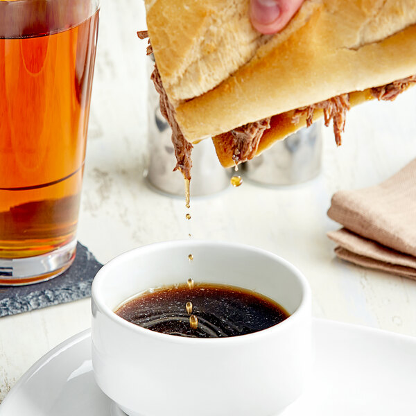 A person pouring Campbell's Au Jus Gravy over a sandwich.
