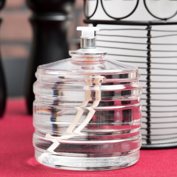 A clear plastic container with a silver lid and a clear bottle of Sterno liquid candle fuel.