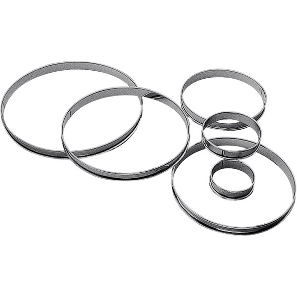 A group of four Gobel stainless steel circular tart rings with rolled edges.