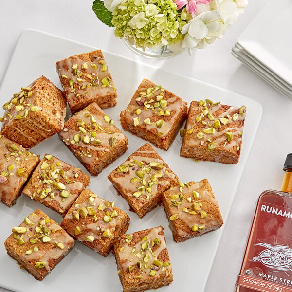 A plate of brownies drizzled with Runamok Cardamom-Infused Maple Syrup and topped with pistachios.