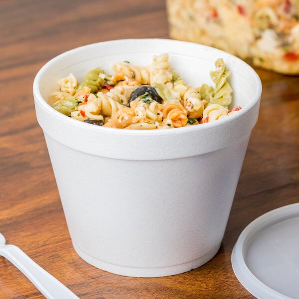 A white Dart foam container filled with pasta and vegetables.