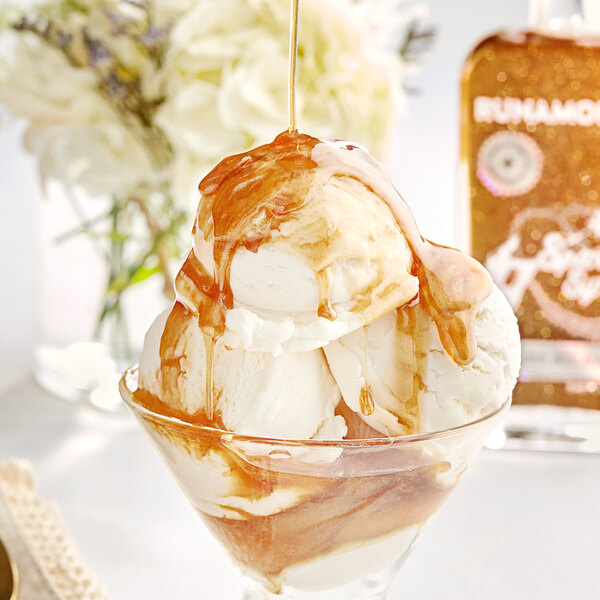 A scoop of Runamok Sparkle Syrup drizzled over a scoop of ice cream in a glass bowl.