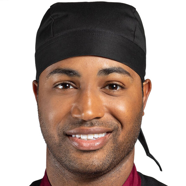 A smiling black man wearing a Uncommon Chef black customizable chef skull cap with ties.