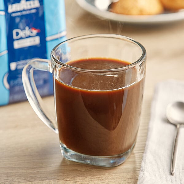 A glass cup of Lavazza decaf coffee next to a spoon.