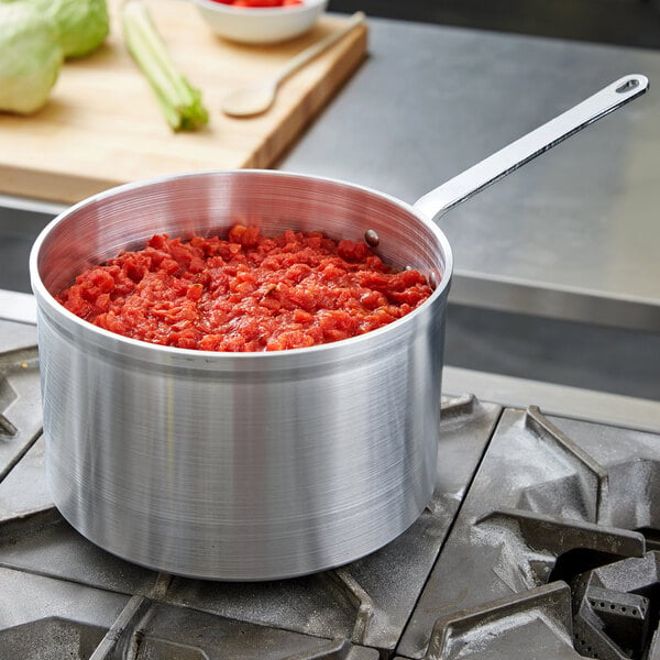 A Vollrath Wear-Ever aluminum sauce pan filled with red food on a stove.