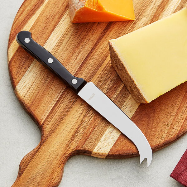 An Acopa stainless steel cheese knife serving cheese on a cutting board.