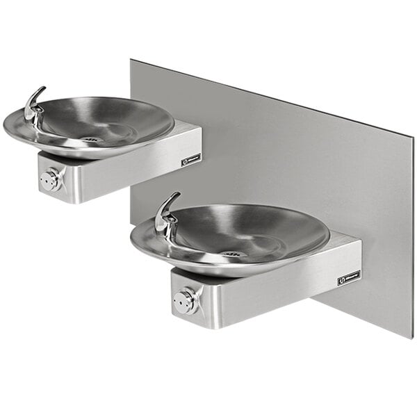 A Haws dual vandal-resistant push-button drinking fountain with mounting system on a wall with two stainless steel fountains.