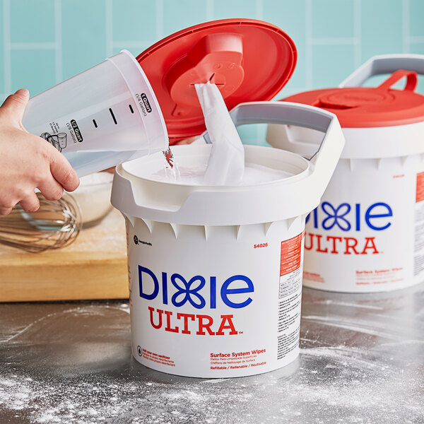 A hand pouring Dixie Ultra Surface System wipes into a dispenser.