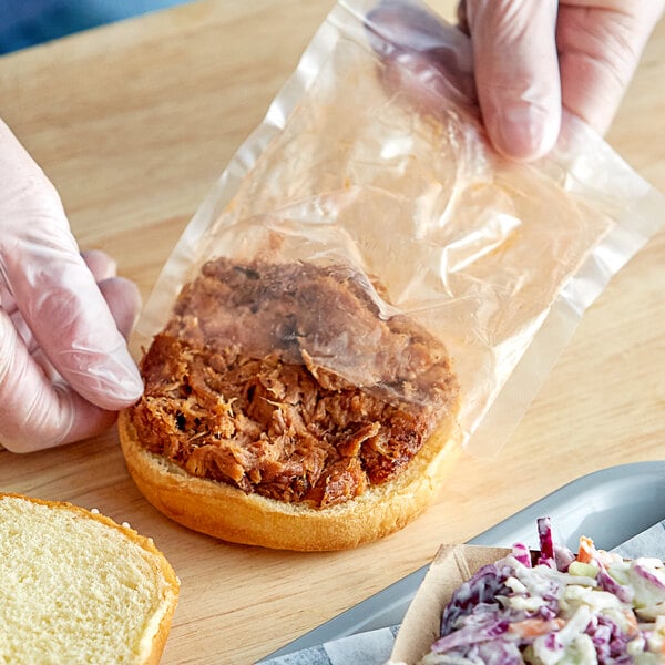 A hand putting Riffs Smokehouse Pulled Pork in a plastic bag.