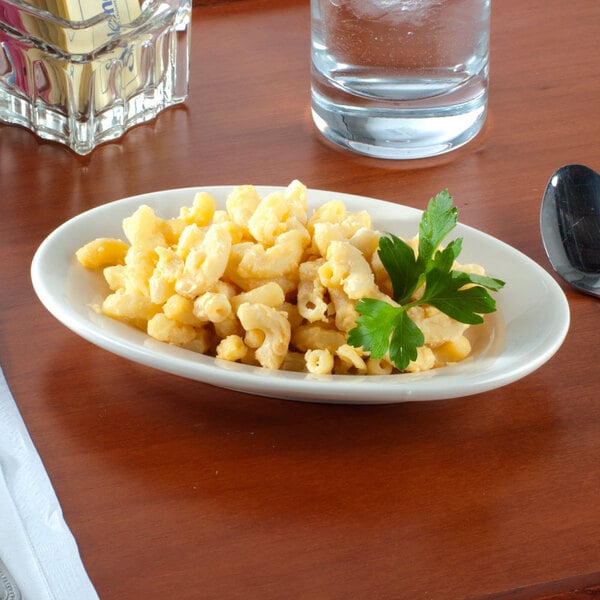 An ivory china platter with macaroni and cheese and parsley on a table.