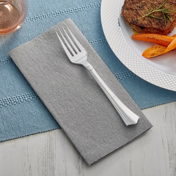 A fork and knife on a Choice Touchstone linen-feel dinner napkin next to a plate.
