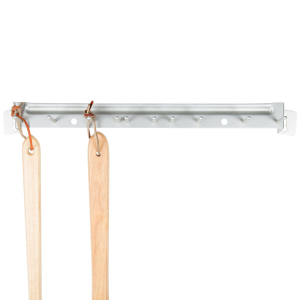 A Carlisle metal rack with wooden handles hanging on it.