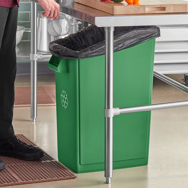 A person standing next to a Lavex green rectangular recycling bin.