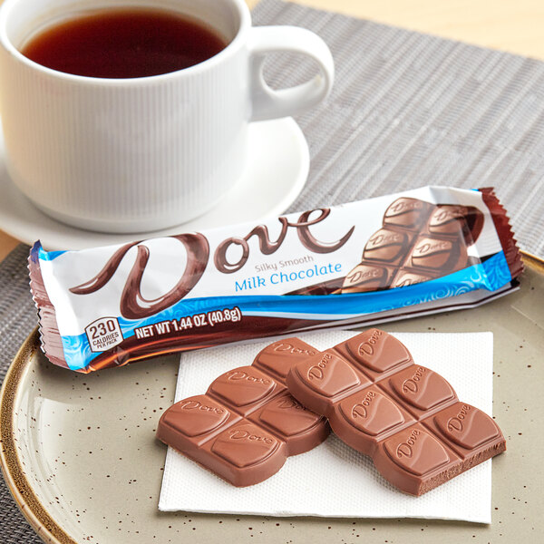 A plate with DOVE milk chocolate bars on it next to a cup of tea.