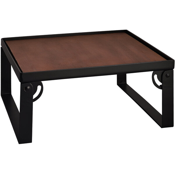 A Spring USA matte black metal square riser with a wood top on a table with a black frame.