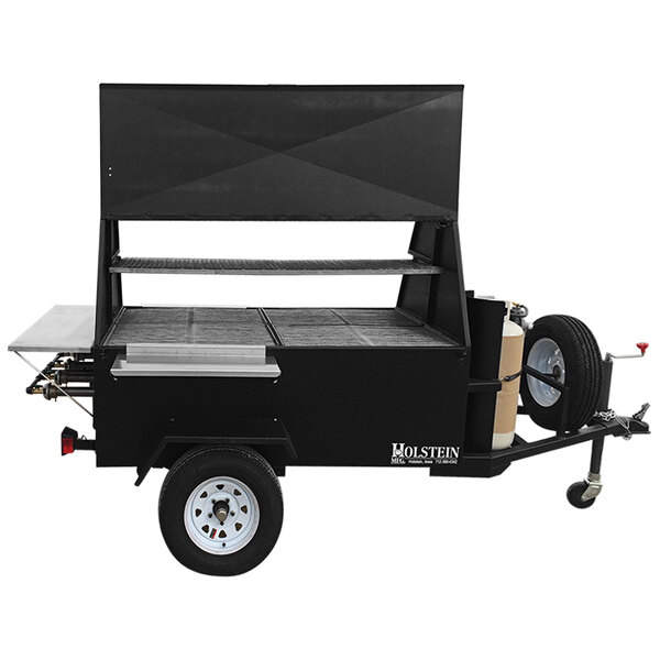 A black cart with a shelf and wheels holding a Holstein Manufacturing towable propane grill.
