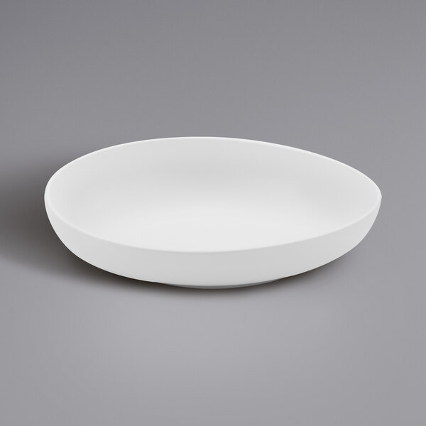 A white GET Enterprises irregular round melamine bowl on a gray surface.