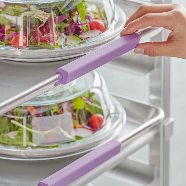 A hand using a purple Baker's Mark bun pan clip to identify a food container of salad.