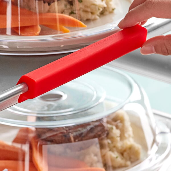 A person using a red Baker's Mark silicone pan clip to serve food.