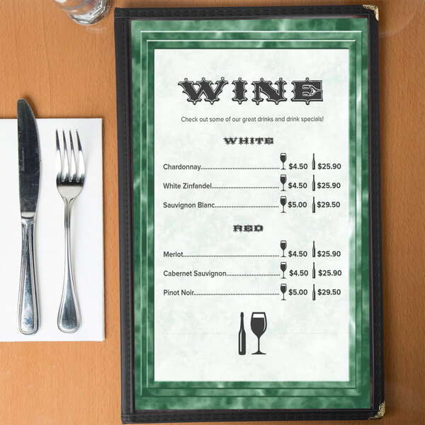 A green marble bordered menu with a knife and fork on a table.