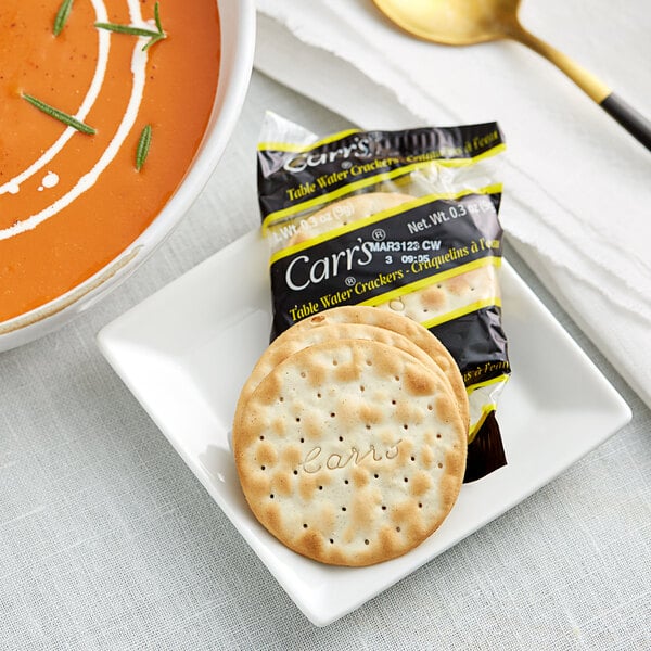 A bowl of Carr's Table Water crackers in soup with a spoon.