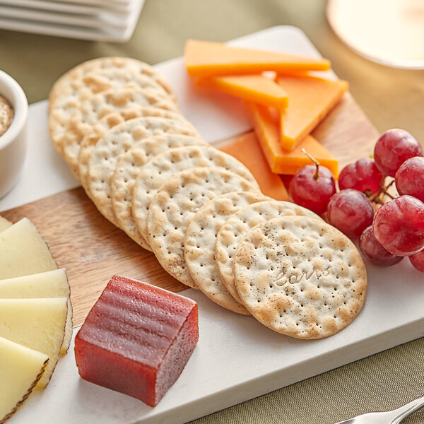 A plate with Carr's Table Water Cracked Pepper Crackers, cheese, and grapes.