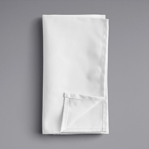 A folded white Oxford cloth napkin on a gray surface.