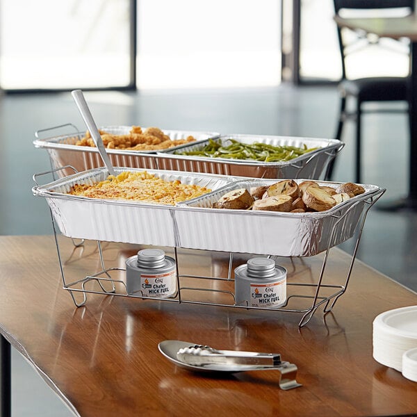 A hotel buffet table with Choice disposable wire chafer stands holding trays of food.