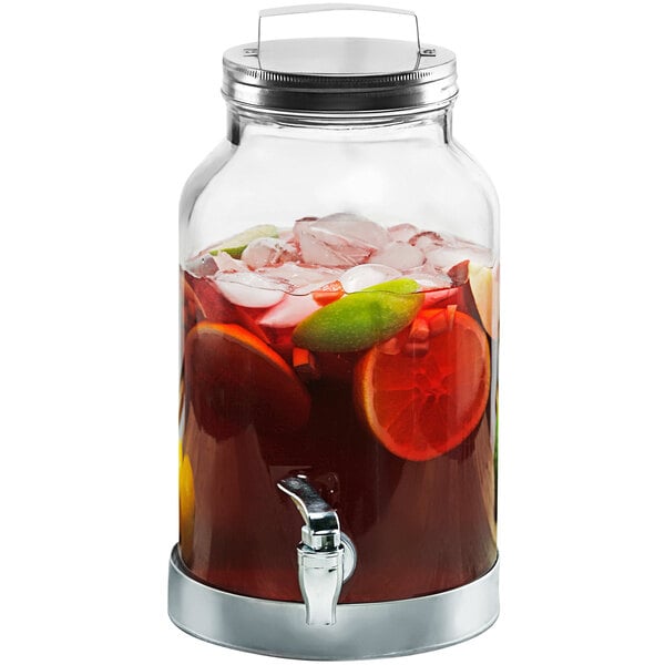 A Stylesetter glass beverage dispenser with drink inside and a galvanized metal lid.