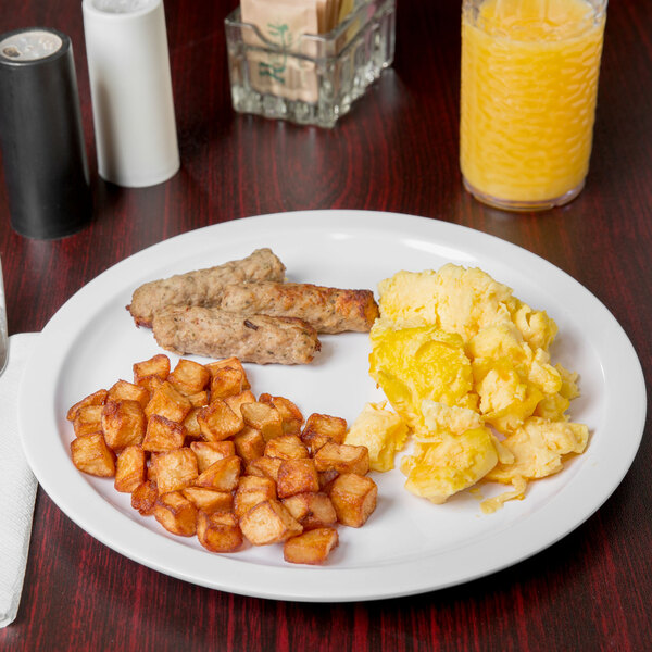 A Carlisle white melamine plate with eggs, sausage, and potatoes on a table.