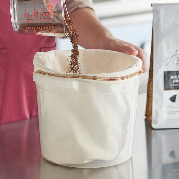 A person using a CoffeeSock Cold Brew 2 Gallon reusable coffee filter to make cold brew coffee.