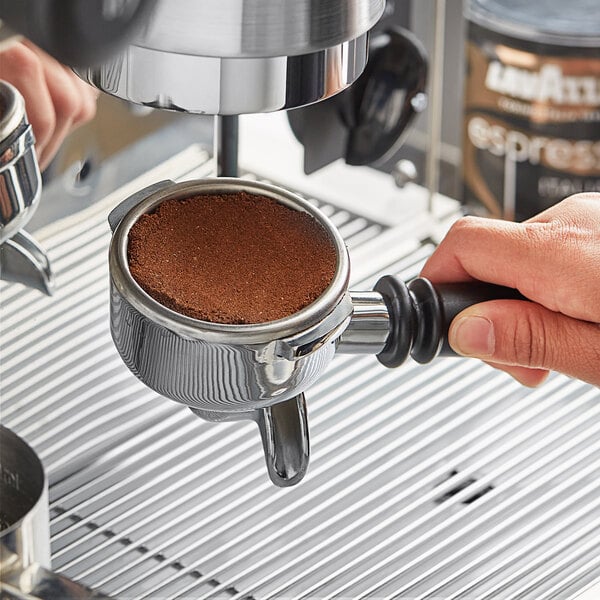 A hand pouring Lavazza Espresso Italiano from an espresso machine.