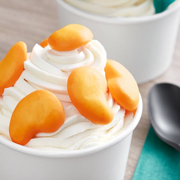A cup of ice cream with orange and white Vidal gummy candies on top.