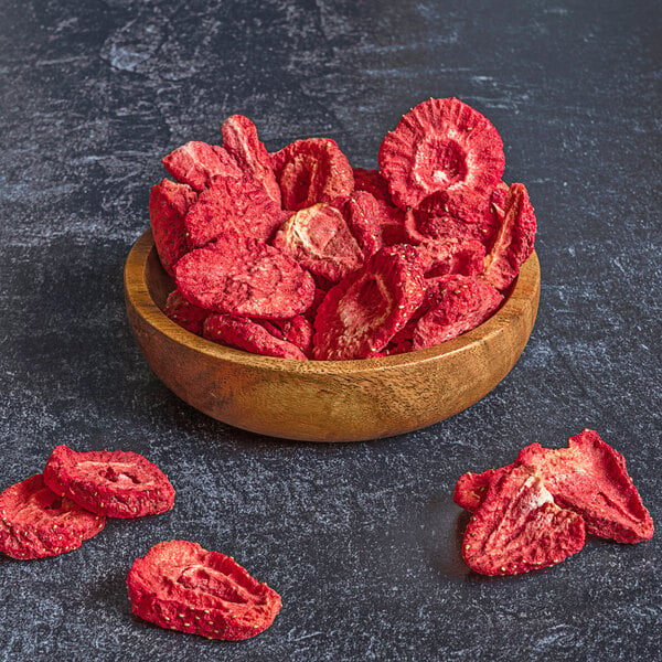 A wooden bowl filled with freeze-dried strawberry slices.