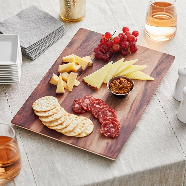 An Acopa walnut faux wood melamine serving board with cheese and grapes on a table.