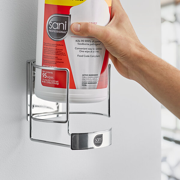A hand using a Sani Professional Wall Bracket to hold a container of wipes.