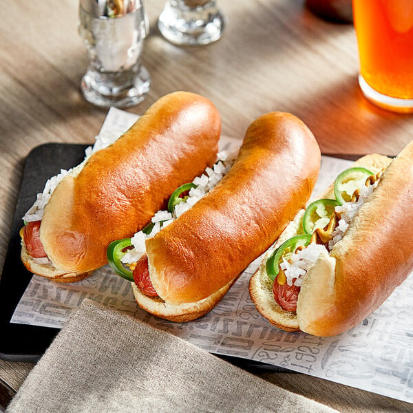 A Turano Gourmet hot dog in a Turano hot dog roll on a table with a group of hot dogs.