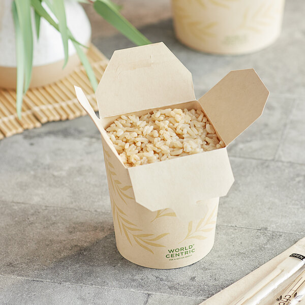 A World Centric Asian take-out container filled with rice with chopsticks and a bamboo spoon.