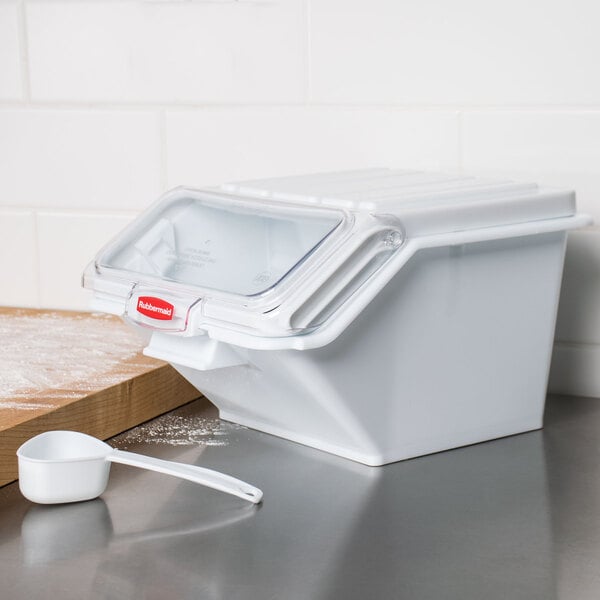 A white Rubbermaid ingredient storage bin with a sliding plastic lid and scoop.