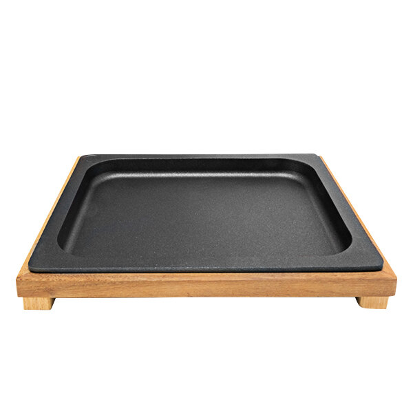 A black square Mibrasa Llauna cooking tray on a wooden stand.