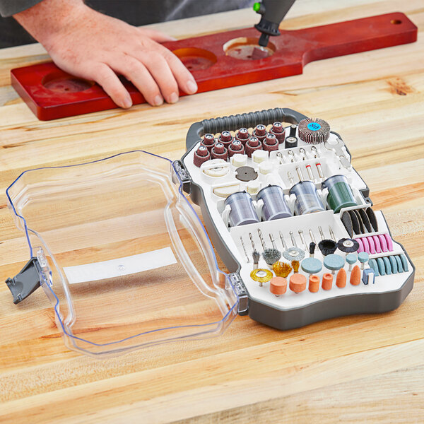 A hand holding a red Genesis rotary tool accessory set case.