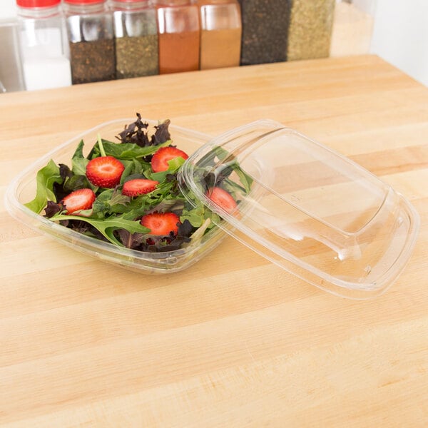 A Sabert clear plastic square bowl with a salad inside and a lid.